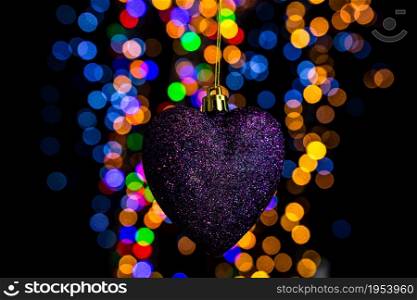 Holding Christmas decoration against bokeh lights background