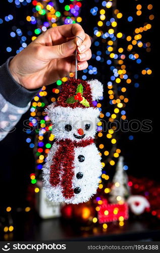 Holding Christmas decoration against bokeh lights background