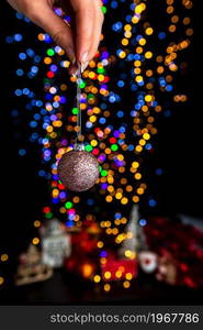 Holding Christmas decoration against bokeh lights background