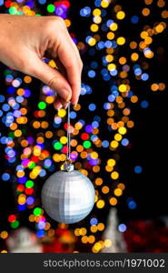 Holding Christmas decoration against bokeh lights background