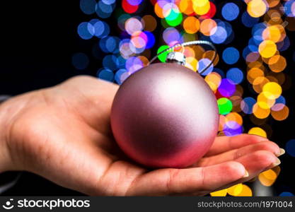 Holding Christmas decoration against bokeh lights background