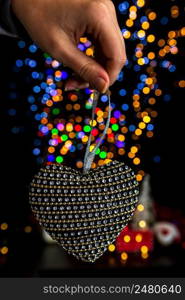 Holding Christmas decoration against bokeh lights background