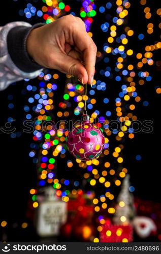 Holding Christmas decoration against bokeh lights background