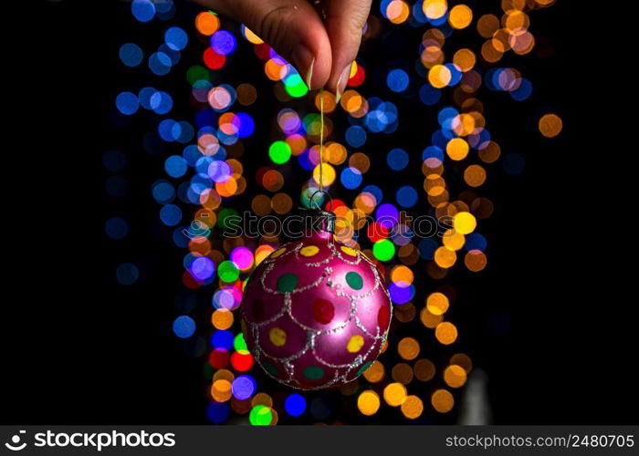 Holding Christmas decoration against bokeh lights background