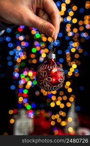 Holding Christmas decoration against bokeh lights background