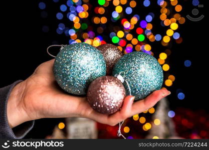 Holding Christmas decoration against bokeh lights background