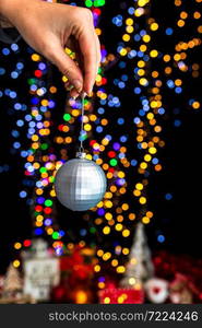 Holding Christmas decoration against bokeh lights background