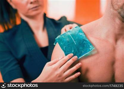 Holding the blue ice pack on the painful shoulder. 