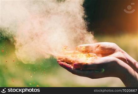 Holi powder held in woman’s hand and a cloud of colorful dust. Holi celebration.. Holi powder held in woman’s hand and a cloud of dust