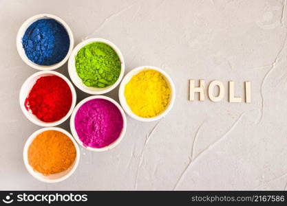 holi text near different type color powder concrete background
