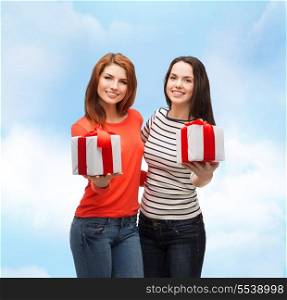 holiday and happiness concept - two smiling teenage girls with presents
