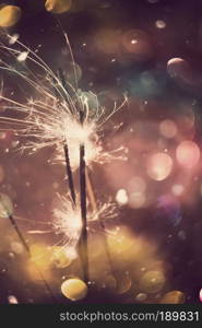 Holiday background with bright bengal fire and colorful bokeh lights.