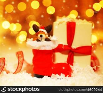 Holiday background with cute Santa boot Christmas tree decorative ornament &amp; gift box in snow over abstract defocus lights&#xA;
