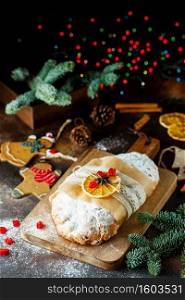 Holiday baking. Christmas cake. Composition of stollen, spruce branches, Christmas tree decorations, cones, dry slices of oranges, berries and spices
