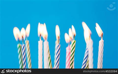 holiday, celebration and party concept - birthday candles burning over blue background and extinguished