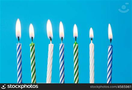 holiday, celebration and party concept - birthday candles burning over blue background and extinguished