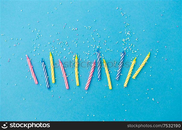 holiday, celebration and party concept - birthday candles with sprinkles on blue background. birthday candles with sprinkles on blue background