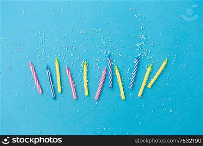 holiday, celebration and party concept - birthday candles with sprinkles on blue background. birthday candles with sprinkles on blue background