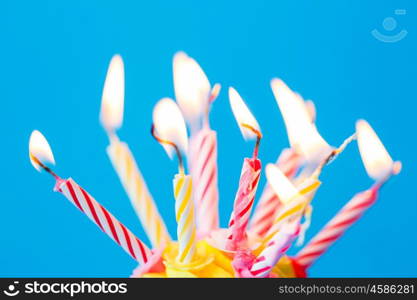 holiday, celebration, greeting and party concept - birthday cupcake with many burning candles over blue background