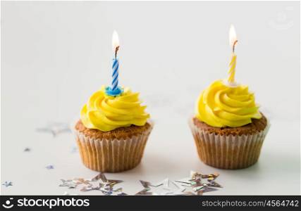 holiday, celebration, greeting and party concept - birthday cupcakes with burning candles