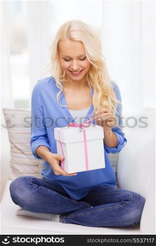 holiday, celebration, home and birthday concept - smiling young woman with gift box at home