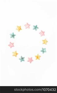 Holiday composition. New Year or Christmas pattern flat lay top view Xmas holiday celebration decorative color stars round wreath frame on white background with copy space. Template of greeting card