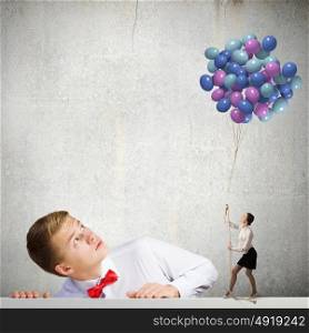 Holiday concept. Businessman looking at woman holding bunch of colorful balloons