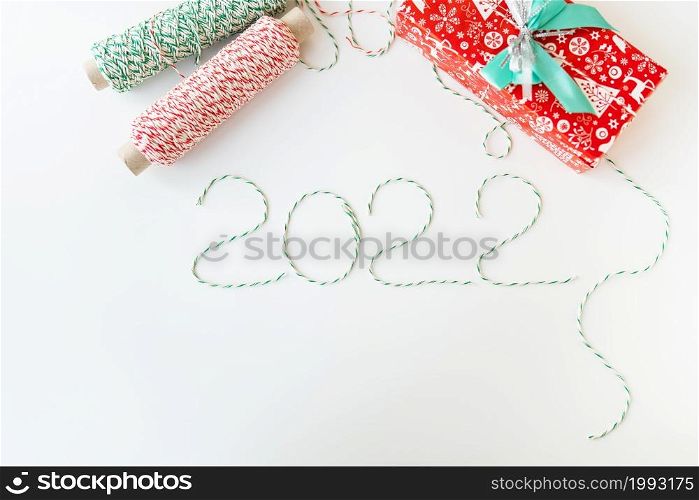 Holiday concept for Christmas and New Year 2022. Layout of various Christmas attributes - hat, sock, striped threads for packaging. View from above. Holiday concept for Christmas and New Year 2022. Layout of various Christmas attributes - hat, sock, striped threads for packaging. View from above.