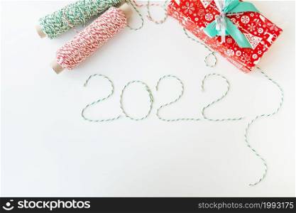 Holiday concept for Christmas and New Year 2022. Layout of various Christmas attributes - hat, sock, striped threads for packaging. View from above. Holiday concept for Christmas and New Year 2022. Layout of various Christmas attributes - hat, sock, striped threads for packaging. View from above.