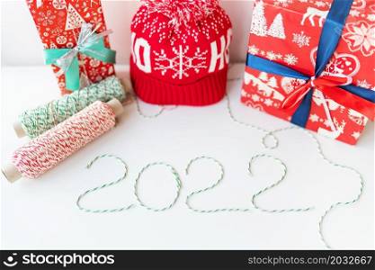 Holiday concept for Christmas and New Year 2022. Layout of various Christmas attributes - hat, sock, striped threads for packaging. Holiday concept for Christmas and New Year 2022. Layout of various Christmas attributes - hat, sock, striped threads for packaging.