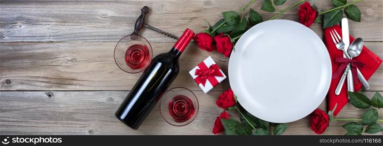 Holiday Dinner setting with red wine and roses on rustic wood in flat lay view