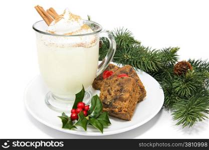 Holiday eggnog with fruitcake, isolated on white with holly and pine garnish.