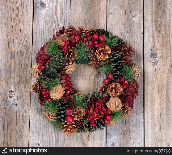 Holiday evergreen and berry wreath on top of rustic wood