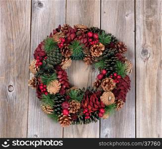 Holiday evergreen and berry wreath on top of rustic wood