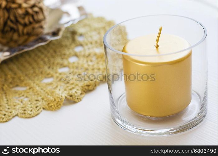 holiday golden candle. holiday golden candle in a glass over a white table