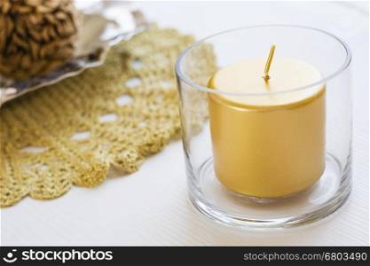 holiday golden candle. holiday golden candle in a glass over a white table