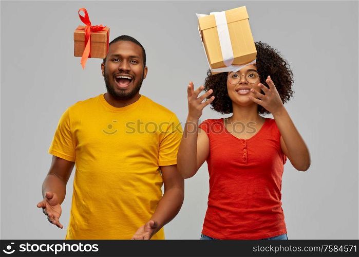 holiday, greeting and people concept - happy smiling african american couple throwing gift boxes over grey background. happy african american couple throwing gift boxes