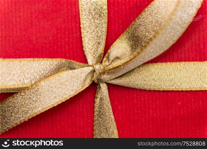 holiday, greeting and surprise concept - close up of christmas red gift box with golden bow. close up of christmas red gift box with golden bow