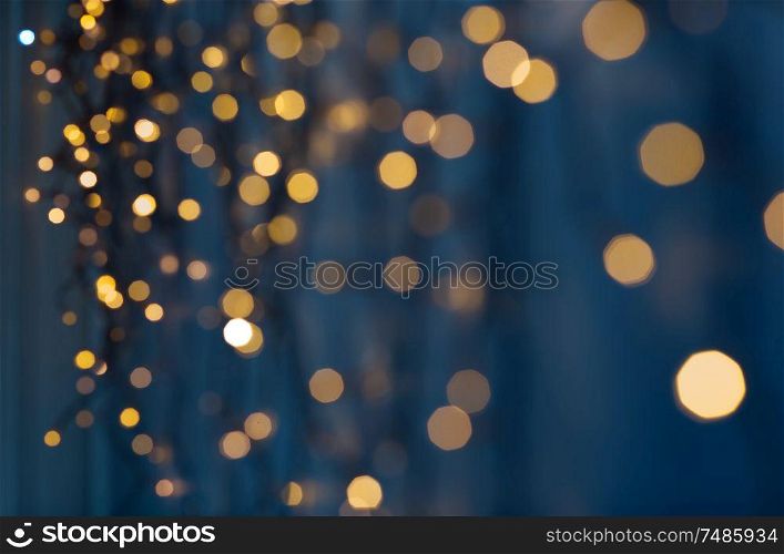 holiday, illumination and decoration concept - bokeh of christmas garland lights over dark blue background. christmas garland lights over dark blue background