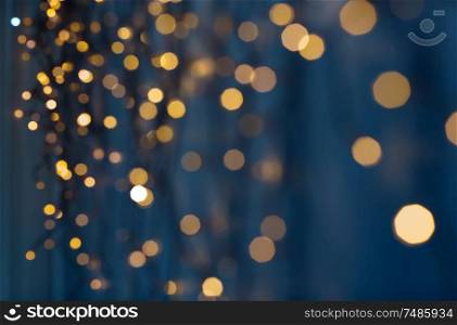 holiday, illumination and decoration concept - bokeh of christmas garland lights over dark blue background. christmas garland lights over dark blue background