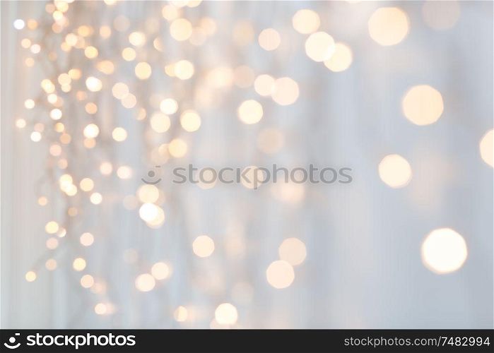 holiday, illumination and decoration concept - bokeh of christmas garland lights over grey background. christmas garland lights over grey background