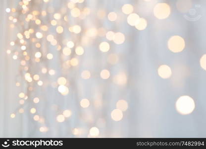 holiday, illumination and decoration concept - bokeh of christmas garland lights over grey background. christmas garland lights over grey background