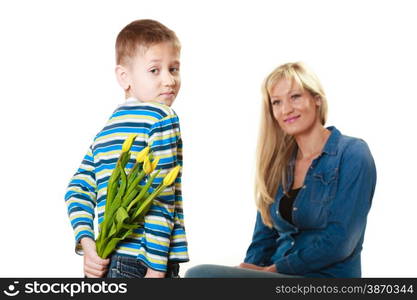 Holiday mother&#39;s day concept. Rear view little boy with bunch of yellow tulips behind back preparing nice surprise for his mother isolated on white