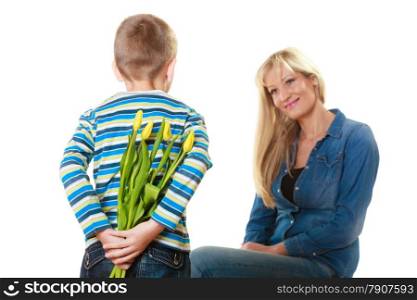 Holiday mother&#39;s day concept. Rear view little boy with bunch of yellow tulips behind back preparing nice surprise for his mother isolated on white