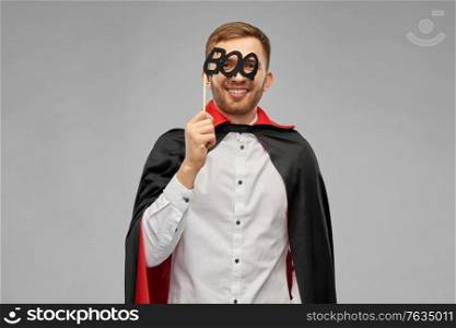 holiday, photo booth and people concept - happy smiling man in halloween costume of vampire and dracula cape with party accessory over grey background. happy man in halloween costume of vampire