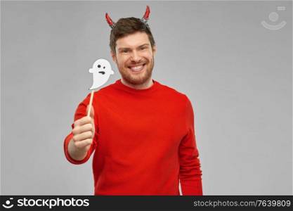 holiday, photo booth and people concept - happy smiling man in halloween costume of devil with party accessory over grey background. happy man in halloween costume of devil over grey