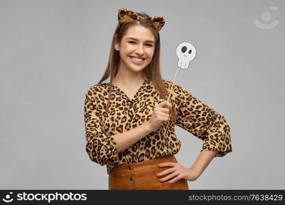 holiday, photo booth and people concept - happy smiling woman in halloween costume of leopard with ears and scull party accessory over grey background. happy woman in halloween costume of leopard