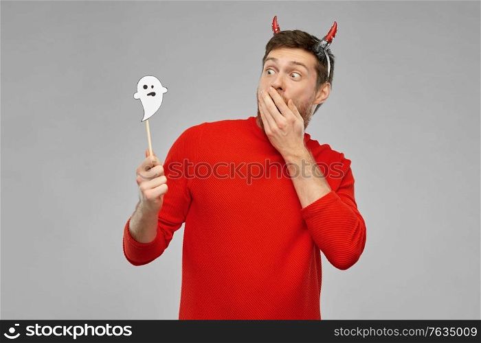 holiday, photo booth and people concept - man in halloween costume of devil with party accessory over grey background. man in halloween costume of devil over grey