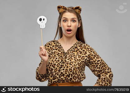 holiday, photo booth and people concept - surprised woman in halloween costume of leopard with ears and scull party accessory over grey background. surprised woman in halloween costume of leopard