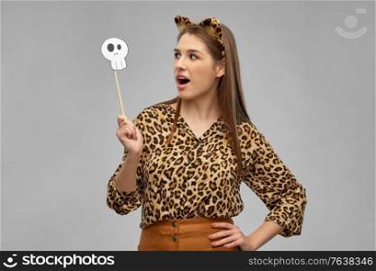 holiday, photo booth and people concept - surprised woman in halloween costume of leopard with ears and scull party accessory over grey background. surprised woman in halloween costume of leopard